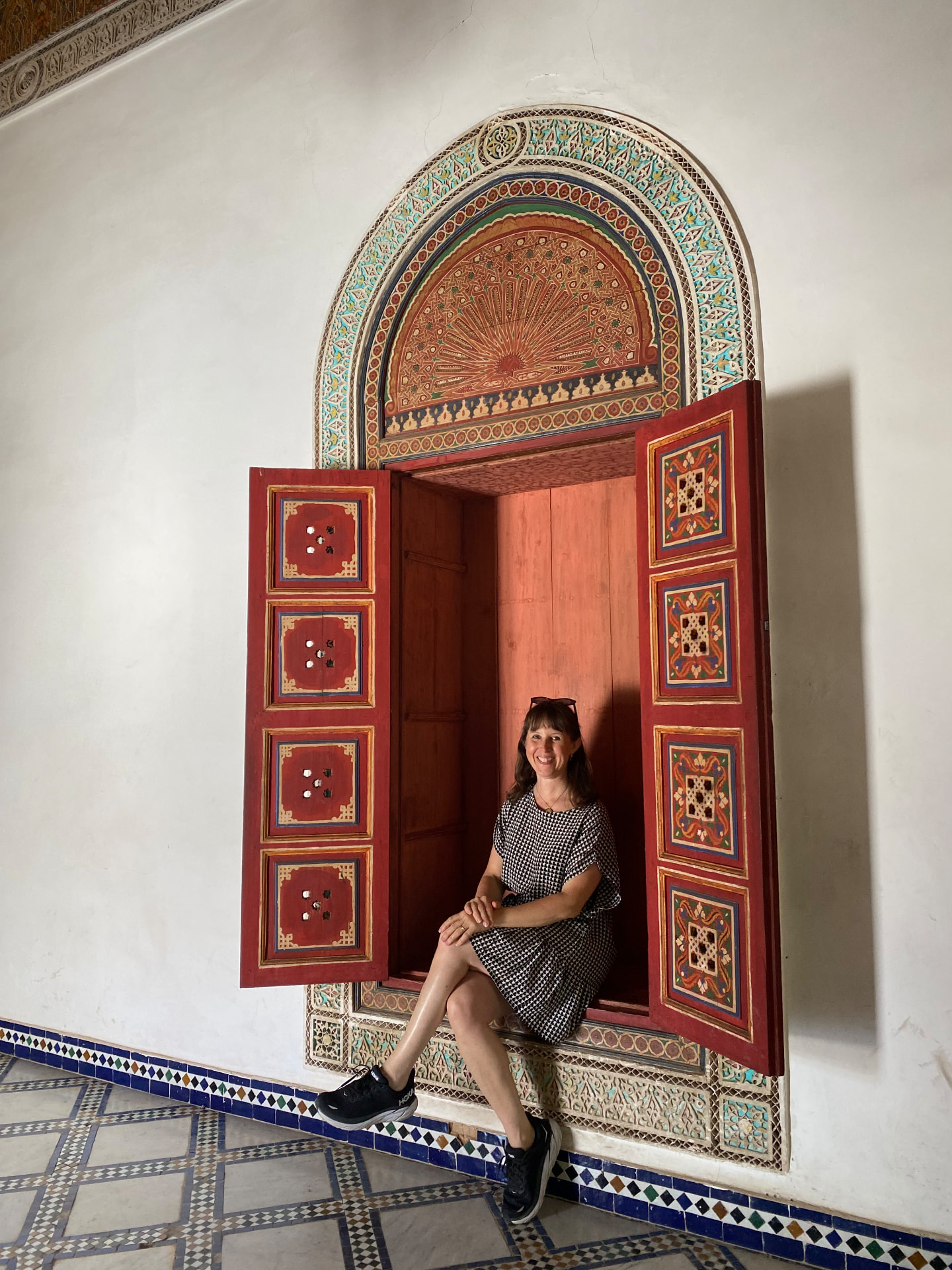 Kristiina Michelsson seated in a hand-painted arched doorway in Marrakech — context, craft and identity meeting in one detail