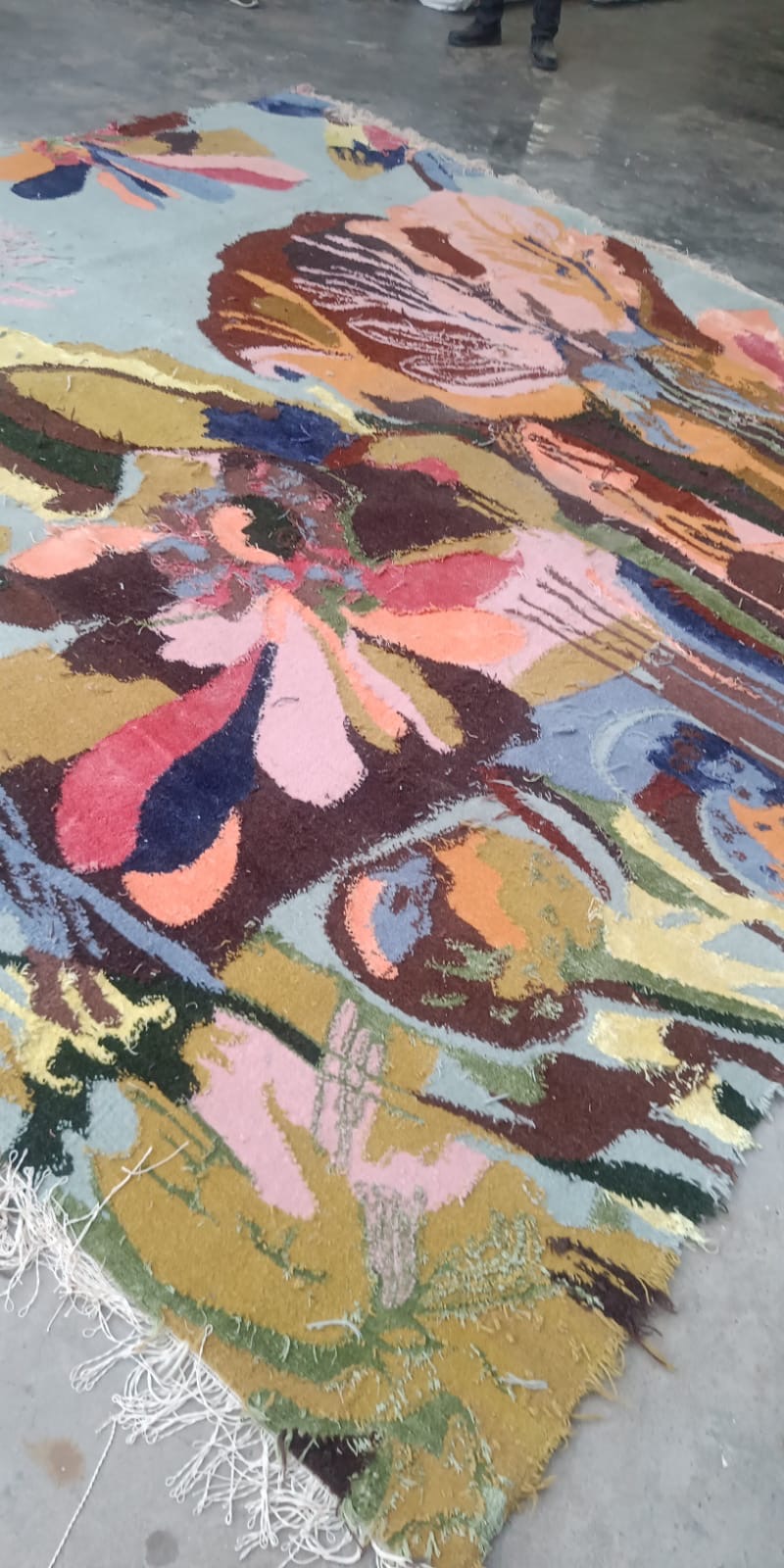 The finished hand-woven carpet laid out, showing its painterly floral motif